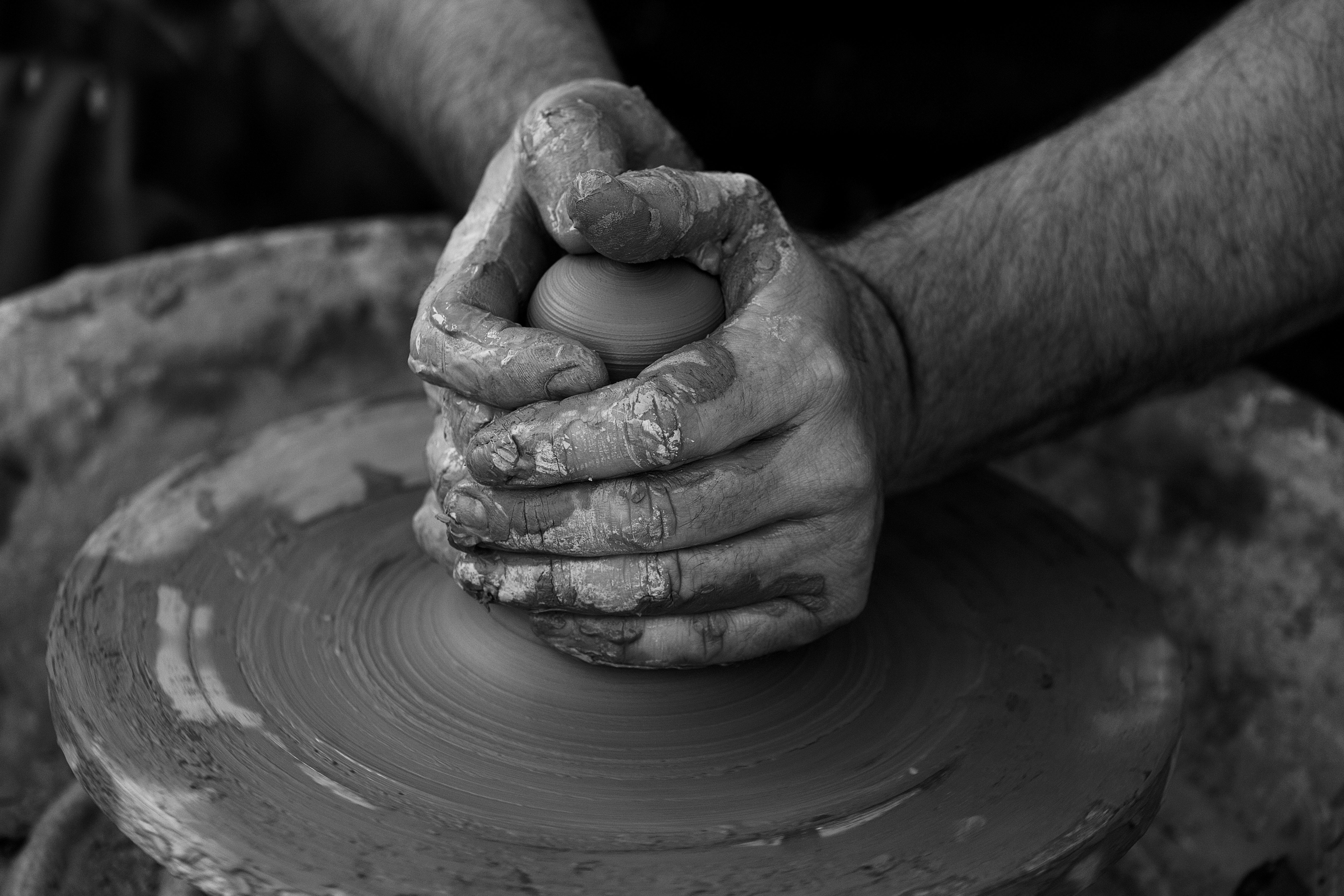 grayscale photography of person's hand making pot